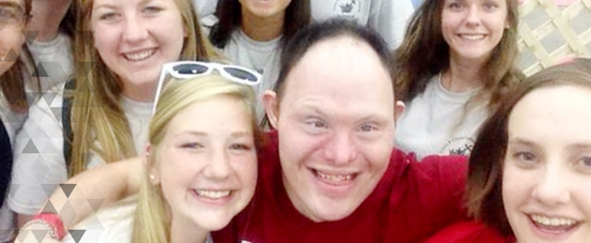 A group of young men and women smile up at a camera.