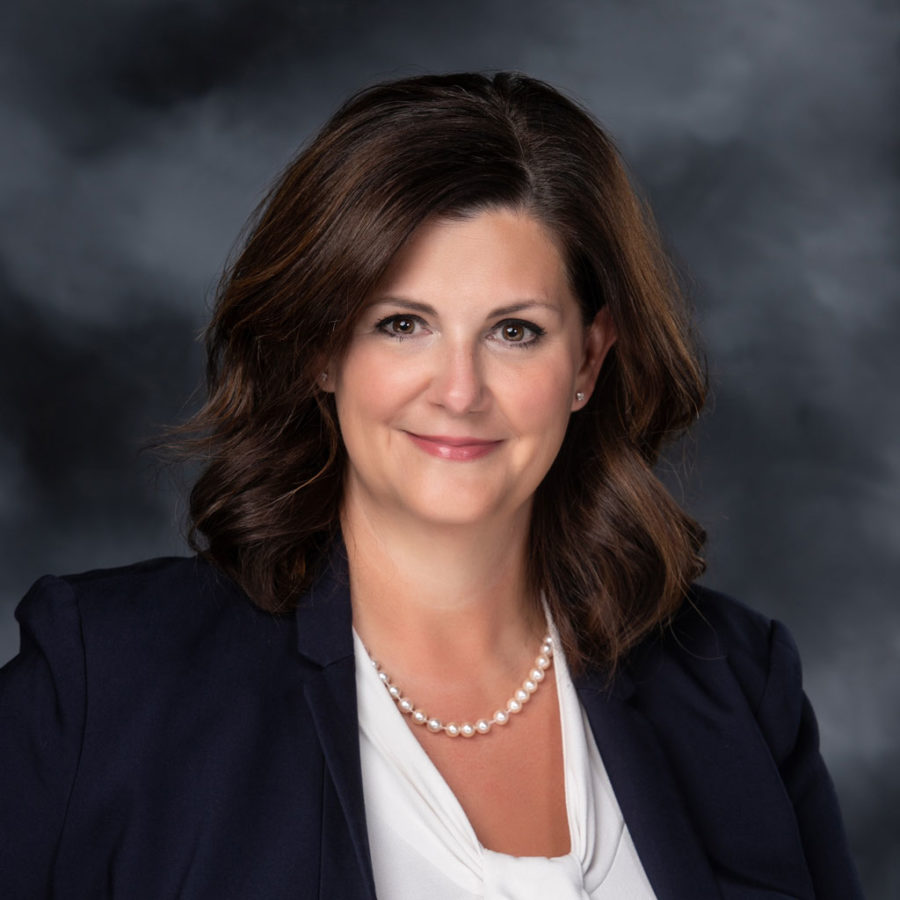 Jenniffer LeDoux, a woman with light skin and brown hair, smiles at the camera.